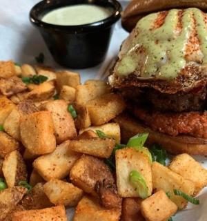 a plate with a hamburger and potatoes and sauce
