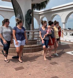 skupina žen stojící před sochou