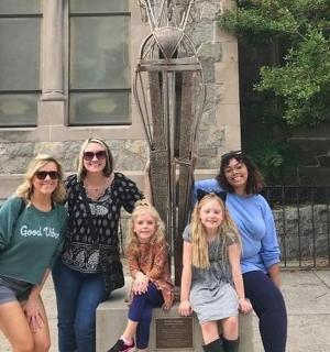 a group of women sitting on a bench in front of a building