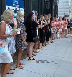 a group of women standing in line on a sidewalk