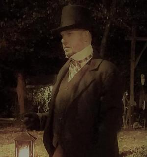 muž v obleku a cylindru stojící vedle lucerny