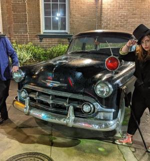 a man and a woman standing next to an old car