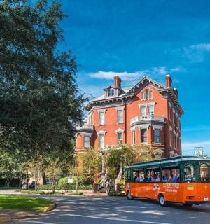 an orange bus driving down a street in front of a building