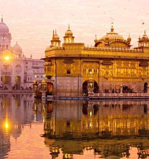 a golden temple with its reflection in the water