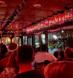 a group of people sitting on a bus with christmas lights