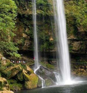 sekumpulan orang berdiri di hadapan air terjun
