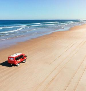 červený nákladní vůz zaparkovaný na pláži u oceánu