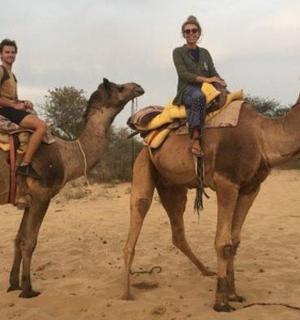 two people are riding on camels in the desert
