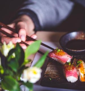 a person is eating sushi with chopsticks on a table
