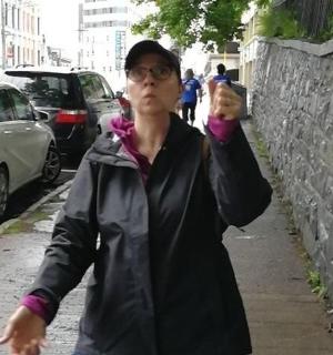 a woman walking down a sidewalk holding a stuffed animal