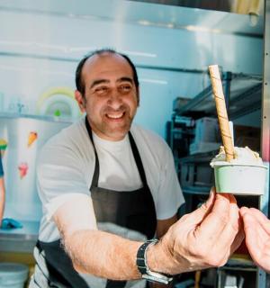 a man in a kitchen giving a person a piece of food