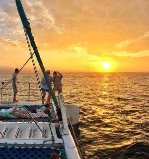 skupina lidí na lodi v oceánu při západu slunce