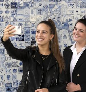 两名女子站在墙前拍照