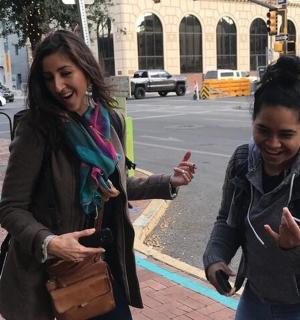 两个女人走在街上，看着她们的手机