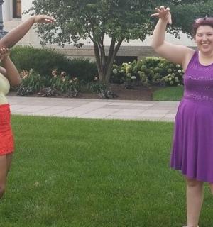 two women standing in the grass with their arms in the air