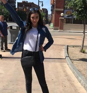 a woman standing on a sidewalk with her arm in the air