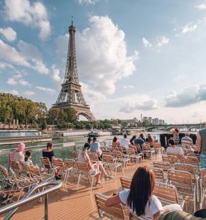 坐在埃菲尔铁塔前的船上的人们