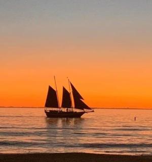 plachetnice v oceánu při západu slunce