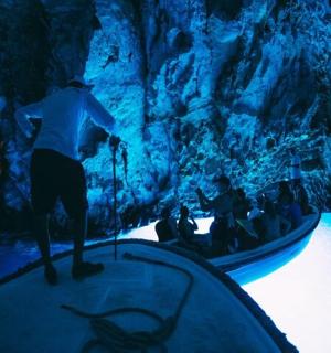 一名男子站在山洞里的舞台上，手握一艘船