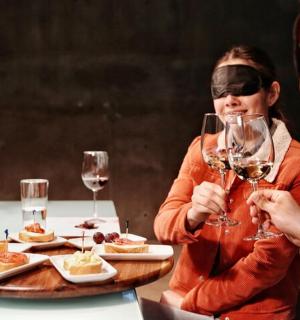 一位女士坐在桌边,手里拿着几杯葡萄酒