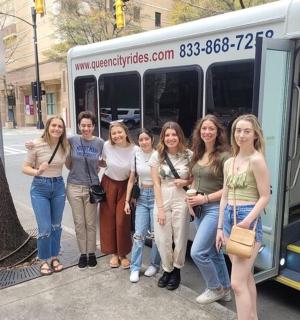 a group of women standing in front of a bus