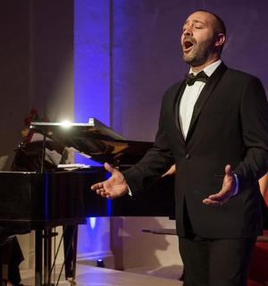 一位身穿燕尾服的男士站在钢琴旁