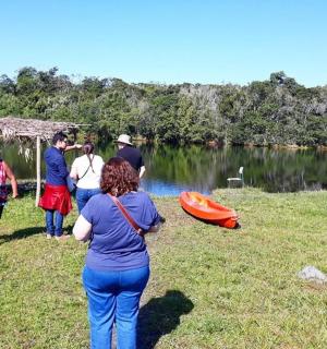 a group of people walking on the grass near a lake