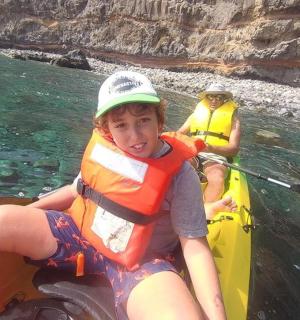 一个小男孩坐在水中的皮划艇上