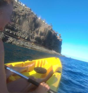 一名女子在海中划着一艘黄色皮划艇