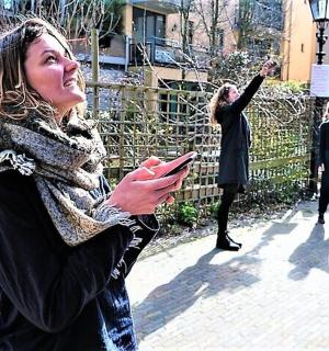 a woman standing on a sidewalk looking at her cell phone