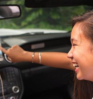 mladá dívka držící mobilní telefon v autě