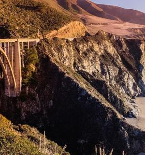 a bridge on a mountain next to the ocean