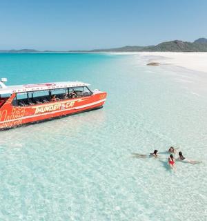 a red boat in the water next to a beach