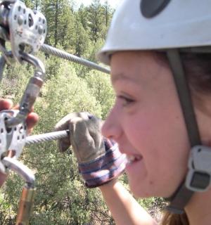 一名戴着头盔的女子正悬挂在滑索上