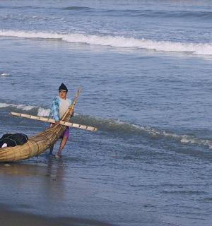 a woman is standing in a boat on the beach