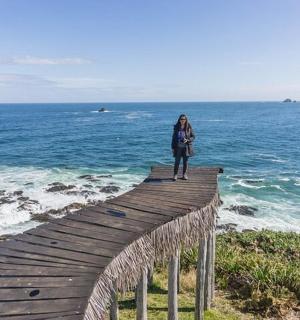 一位女士站在横跨大海的木桥上
