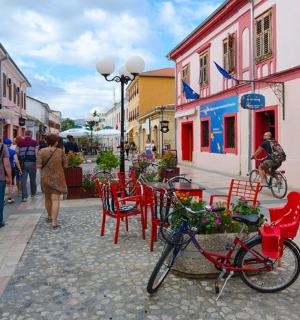 a street with tables and chairs and people walking down the street
