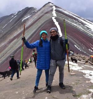 a man and woman standing on top of a snow covered mountain