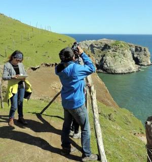 一名男子正在为一名女子拍摄大海