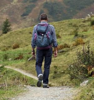 a man with a backpack walking down a trail