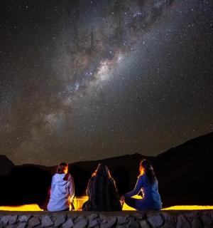 a group of three people sitting around a table looking at the stars
