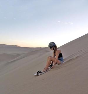 a woman sitting on a snowboard in the desert