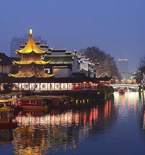 一条河流，河边有一座中国建筑，紧邻一座城市