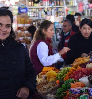 a woman standing in front of a market with people