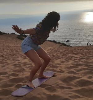 a little girl standing on a surfboard on the beach