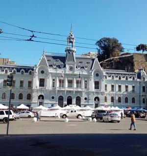 ein großes weißes Gebäude mit auf einem Parkplatz geparkten Autos