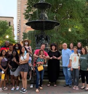 skupina lidí stojící před fontánou