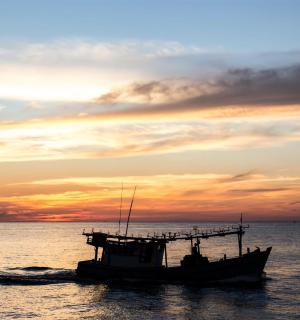 海上的一艘船，背景是日落