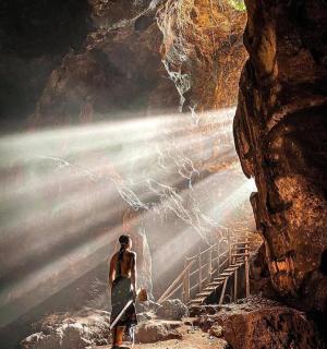 一位妇女站在山洞里望着瀑布