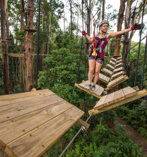一名女子站在森林里的秋千上
